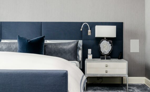 white and clear desk lamp on white wooden nightstand near bed