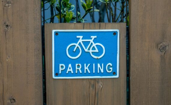 a blue parking sign mounted to a wooden fence