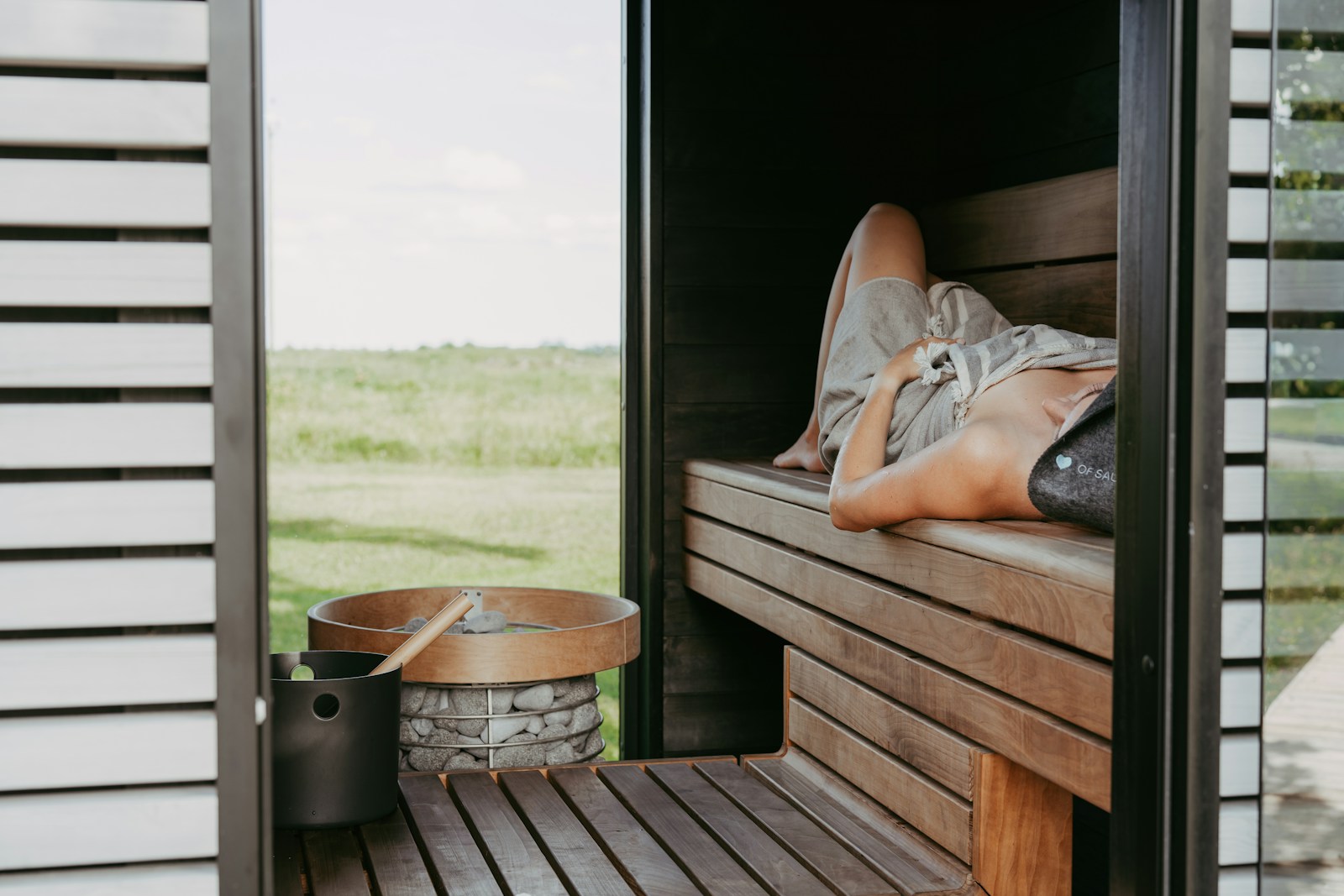 Person relaxing in a wooden sauna with outdoor view.
